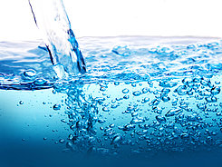 Wasserhaushalt Ein Wasserstrahl fließt in Wasser und verursacht Blasen