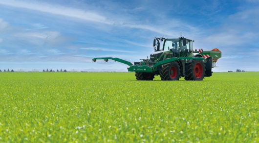 Fendt-Traktor mit NEXT GreenSeeker und Amazone Düngerstreuer auf einem Feld bei blauem Himmel