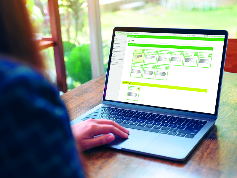 Frau sitzt vor Laptop und sieht sich die NEXT Farming LIVE Software an.